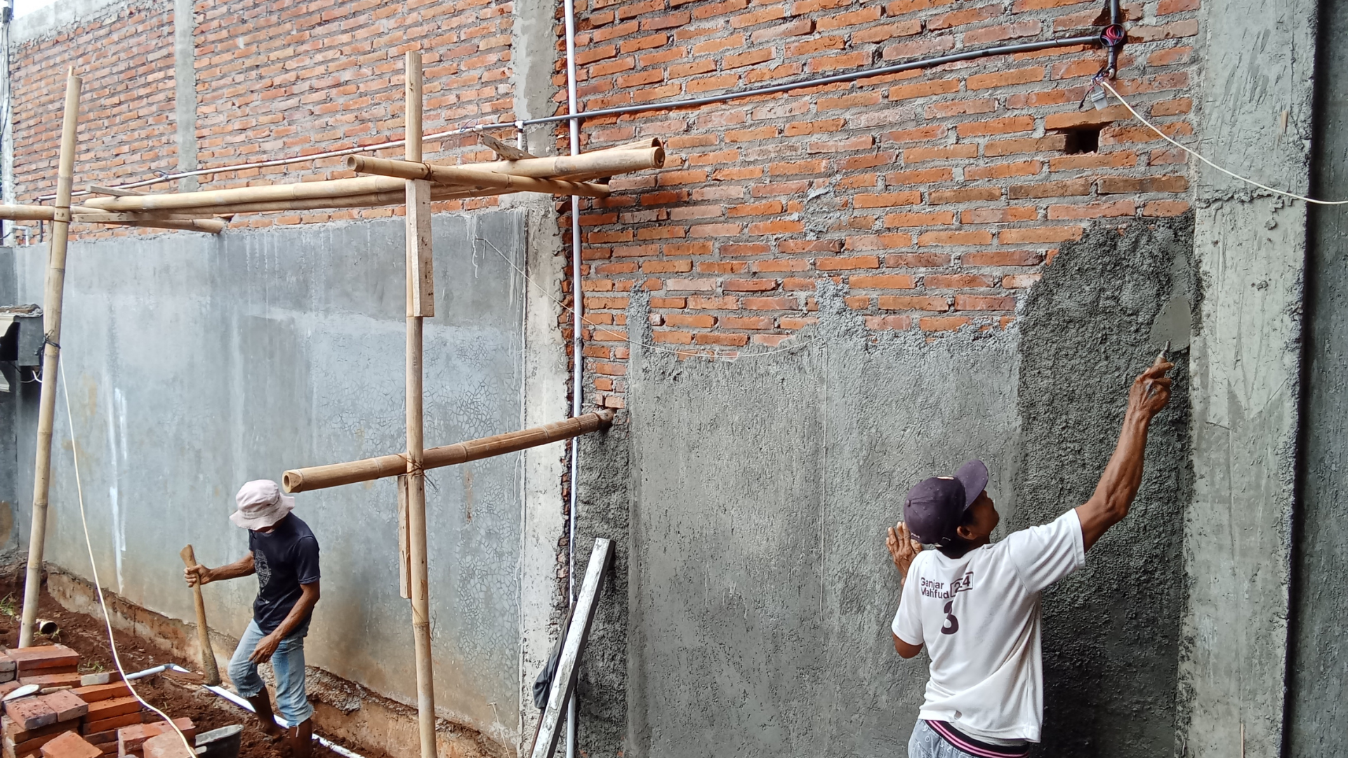 Workers applying plaster to a wall